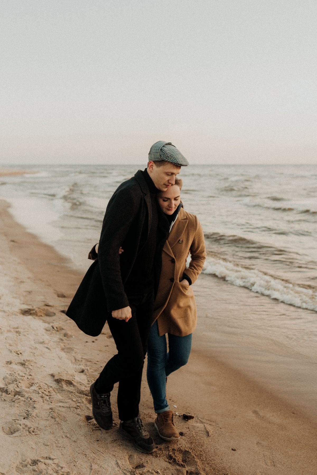 Una pareja camina abrazada junto al mar