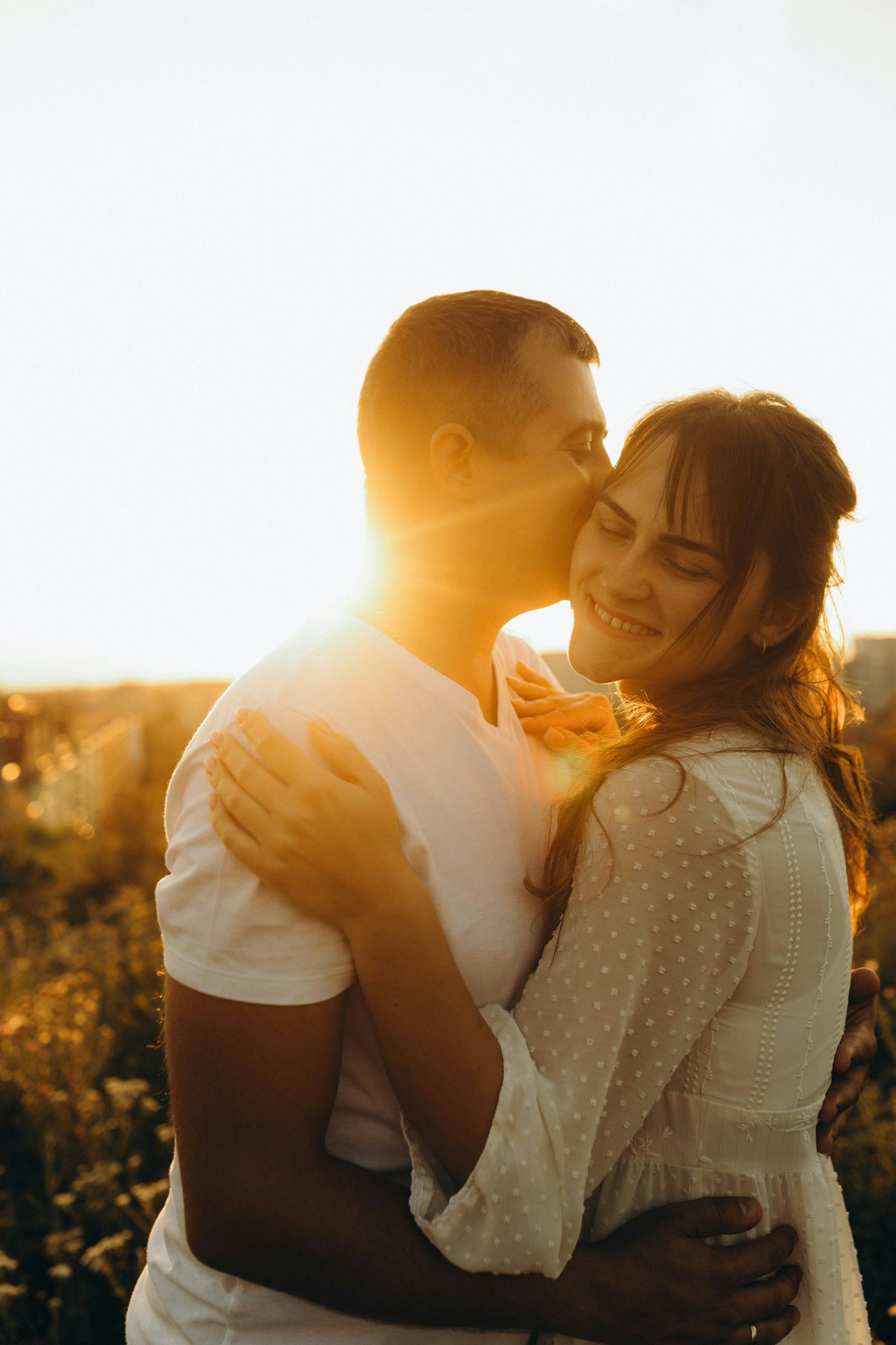 Una pareja abrazada comparte un momento de ternura bajo la luz del sol